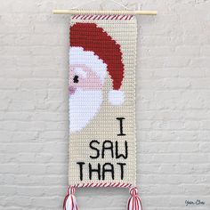 a cross stitch christmas banner hanging on a brick wall with the words i saw that