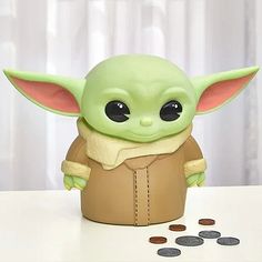 the baby yoda toy is next to some coins