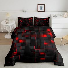 a bed with black and red comforters on top of it in a white room