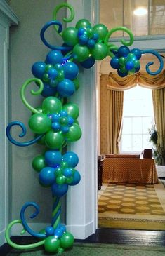 a balloon arch with blue and green balloons hanging from it's sides in front of a doorway