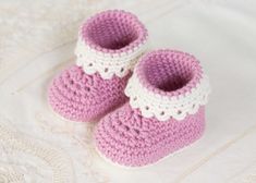 a pair of pink and white crocheted baby booties sitting on top of a bed