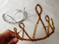 a hand holding a piece of gold wire next to a pair of scissors on a white cloth