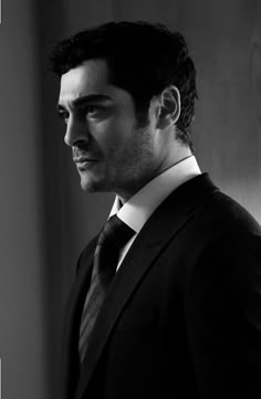 a black and white photo of a man in a suit looking off into the distance