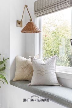 a window sill with two pillows and a lamp on it next to a potted plant