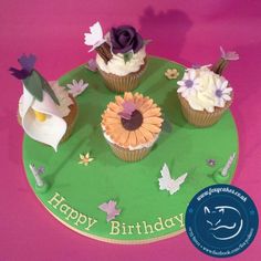 three cupcakes on a green plate with purple and white frosting are arranged in the shape of flowers