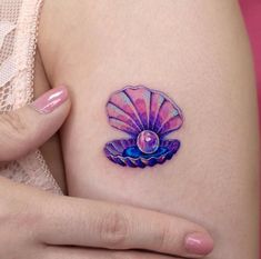 a woman's arm with a tattoo on it that has a pink and blue shell