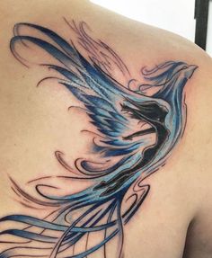 the back of a woman's shoulder with a blue bird tattoo on her chest