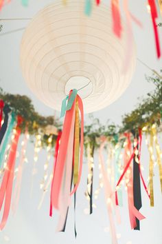 colorful streamers are hanging from the ceiling in front of trees and lights at an outdoor event