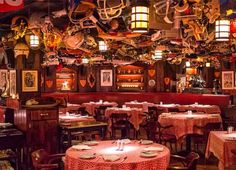 the inside of a restaurant with tables, chairs and lamps hanging from the ceiling above