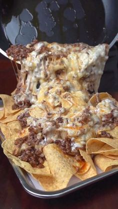 a tray filled with nachos and cheese on top of each other next to a fork