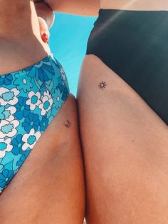 two women in swimsuits standing next to each other with tattoos on their butts