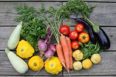 an assortment of fresh vegetables laid out on a wooden surface