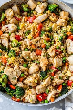 a skillet filled with chicken, broccoli and rice on top of a table