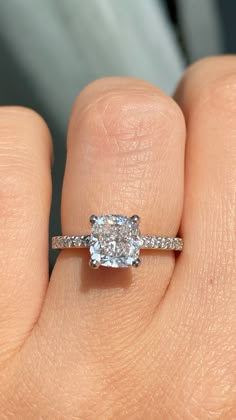 a woman's hand with a diamond ring on top of her finger and an engagement band