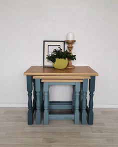 a blue table with a yellow vase on it and a sign that says grace's attic above it