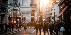 many people are walking down the street at sunset