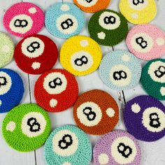 colorful crocheted coasters with numbers and faces are arranged on a white wooden surface