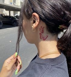 a woman with a butterfly tattoo on her neck is holding a toothbrush to her ear