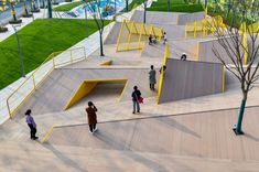 several people are walking around an empty skateboard park with ramps and stairs in the foreground