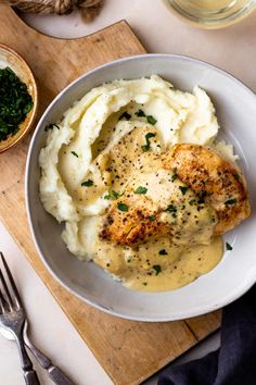 a white bowl filled with mashed potatoes and chicken breast covered in gravy