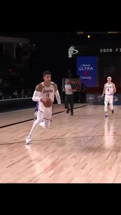 two men are playing basketball on a court with other people watching from the sidelines