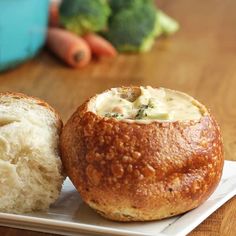 a close up of a bread bowl on a plate with broccoli in the background