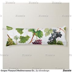 a decorative pillow with grapes and leaves on the front, sitting against a white wall