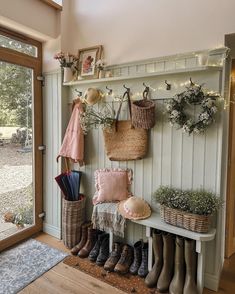 the entryway is decorated with baskets, umbrellas and rain boots on display next to an open door