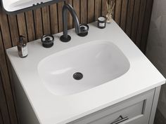 a white sink sitting under a bathroom mirror next to a wooden wall mounted faucet