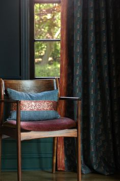 a chair sitting in front of a window with a pillow on it's back