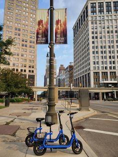 a blue scooter parked next to a street light in front of tall buildings