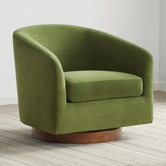 a green chair sitting on top of a rug in front of a white wall and floor