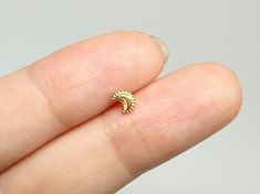 a person's finger with a small gold ring on it