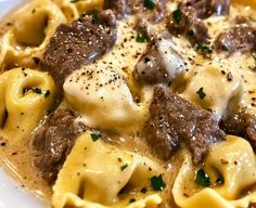 a white plate topped with pasta covered in meat and cheese