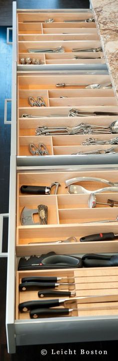 an open drawer with utensils and spoons in it on a counter top