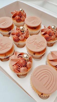 some cupcakes with pink frosting and bows on them in a white box