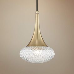 a glass and brass pendant light hanging from a ceiling fixture in a living room or dining room