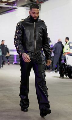 a man in black leather is walking down the street with his hand on his hip