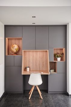 an office with gray walls and wooden shelves on the wall, along with a white chair