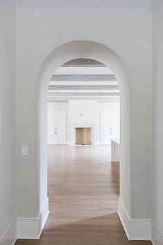 an empty room with white walls and wood floors is seen in this image from the hallway