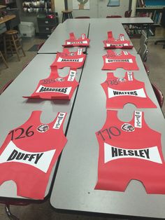 several red and white shirts sitting on top of a table in a room filled with chairs