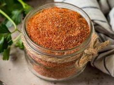 a glass jar filled with spices sitting on top of a counter next to a towel