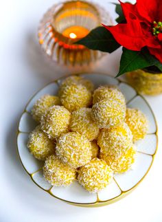 a white plate topped with sugar balls next to a vase filled with red poinsettis