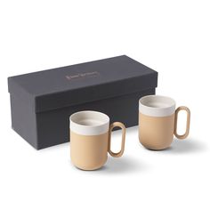 two coffee mugs sitting in front of a black box