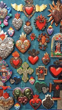 an assortment of heart shaped brooches are displayed on a blue cloth covered table