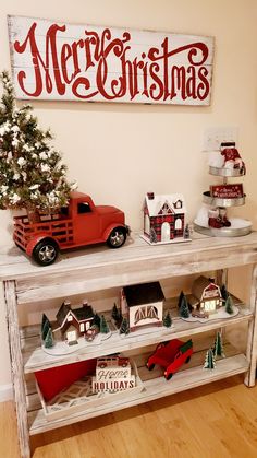 a red truck is parked next to a christmas tree and other decorations on a shelf