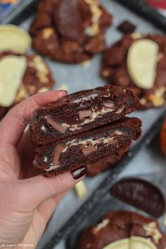 someone is holding up some chocolate cookies with white and brown toppings