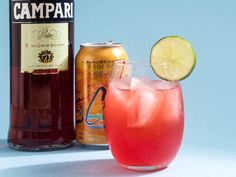 a glass filled with liquid next to a bottle of beer and a lime slice on the rim