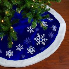 a christmas tree skirt with white snowflakes on it and a blue circle under the tree