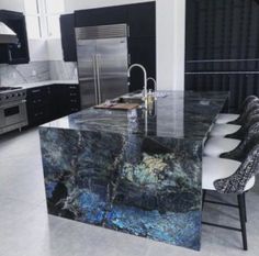 a large kitchen with marble counter tops and stainless steel appliances, along with black cabinets